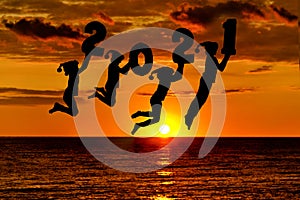 Silhouette of number 2021 in the hands of jumping children. Sunset sky and sea on background. New years concept
