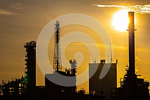 Silhouette of oil and gas refinery industry plant with glitter lighting and sunrise in the morning,