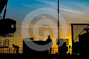 Silhouette of oil and gas wellhead platform and well service worker while working to perforation production tubing gas reservoir.