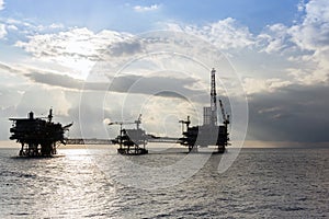 Silhouette of oil production platforms complex connected with bridge