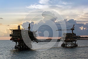 Silhouette of oil production platforms complex connected with bridge