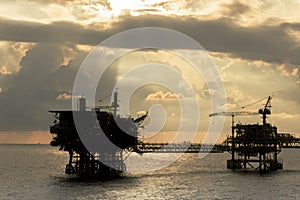 Silhouette of oil production platforms complex connected with bridge