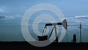 Silhouette of oil pumpjack at sunset. Motion of piston pumps, timelapse.