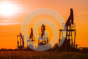 The silhouette of oil pumps in a large oil field at sunrise