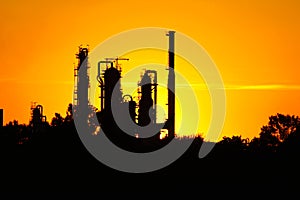 Silhouette of oil refinery factory against sunset