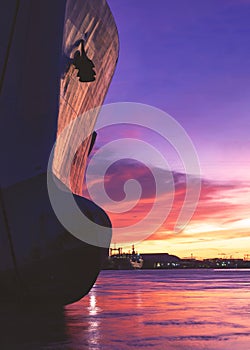 Silhouette oil tanker ship moored at harbor against colorful sunset sky background in evening time and vertical frame