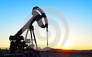 A silhouette of an oil well drilling for oil.