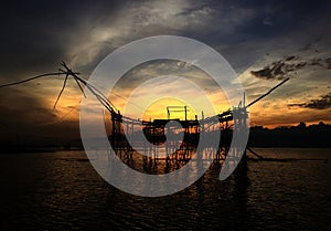 Silhouette of old culture traditional fishing at lake by wooden square dip net in the sunrise of morning time