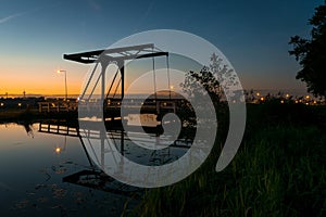 Silhouette of an old dutch bridge under a twilight sky. Beautiful reflections in the water of a canal.