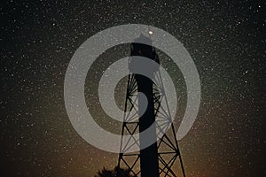 Silhouette of the Old Lighthouse against the background of the starry sky