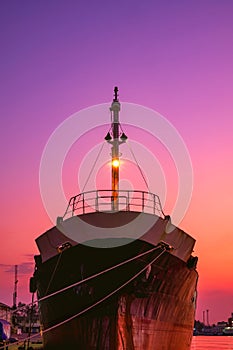 Silhouette of the old oil tanker ship moored in shipyard area at harbor during renovation work against colorful twilight sky