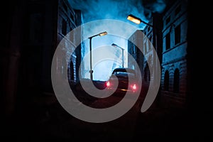 Silhouette of old vintage car in dark foggy toned background with glowing lights in low light, or silhouette of old crime car dark