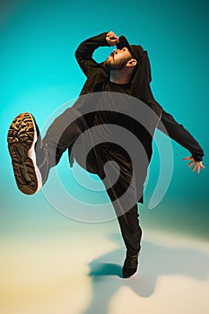 The silhouette of one hip hop male break dancer dancing on colorful background