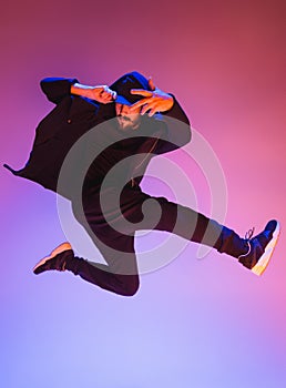 The silhouette of one hip hop male break dancer dancing on colorful background