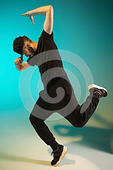 The silhouette of one hip hop male break dancer dancing on colorful background