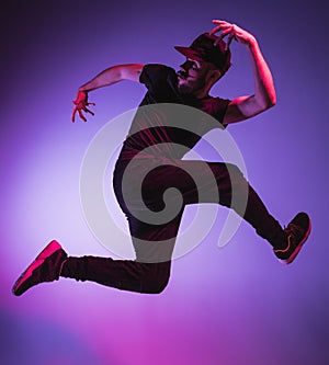 The silhouette of one hip hop male break dancer dancing on colorful background