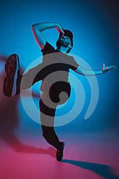 The silhouette of one hip hop male break dancer dancing on colorful background