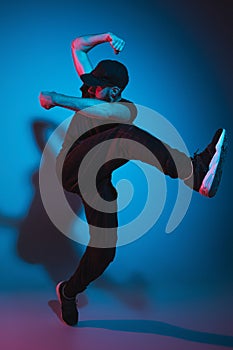 The silhouette of one hip hop male break dancer dancing on colorful background