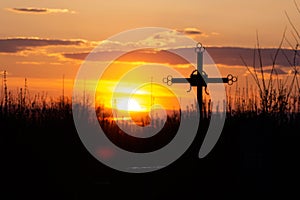 Silhouette orthodox cross grave at cemetery on orange sunset background