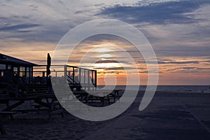 Silhouette of outdoor terrace of beach pavilion `Paal 17` with sunset sea scene in background on island Texel in Netherlands