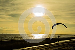 Silhouette of paraglider on the beach with sunset