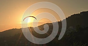 Silhouette paraglider crosses the setting sun in Dharamshala, Himachal Pradesh.