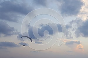 Silhouette of a paraglider in the evening sky hovering over the sea