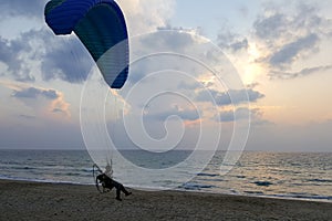 Silhouette of a paraglider in the evening sky hovering over the sea