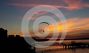 Silhouette of a paraglider in the evening sky with pink clouds