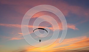 Silhouette of a paraglider in the evening sky with pink clouds