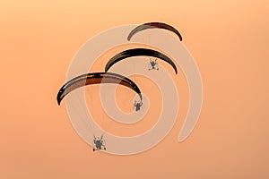 Silhouette of the Paramotor gliding and flying In the air through soft sunlight sky