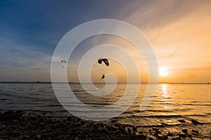 Silhouette of Paramotors flying to sky on sunset