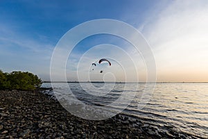 Silhouette of Paramotors flying to sky on sunset