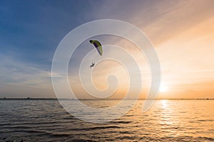 Silhouette of Paramotors flying to sky on sunset