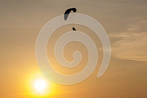 Silhouette of Paramotors flying to sky on sunset Adventure man active extreme sport pilot flying in sky with paramotor engine glid