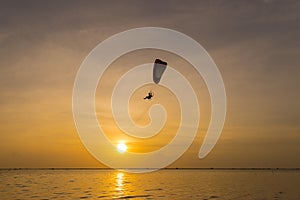 Silhouette of Paramotors flying to sky on sunset