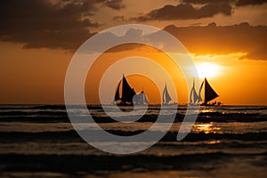 Silhouette Paraw sailing boats under orange sunset