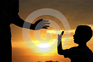 Silhouette parent holds the hand of a  child