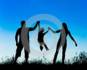 Silhouette of parents and kid having fun spending time