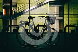 Silhouette of a parked Bicycle on the background of a bright building.