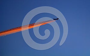 Silhouette of a passenger aircraft in the sky with an inversion trail. The plane takes off at sunset. Abstract composition