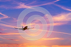 Silhouette passenger airplane flying away in to sky high altitude during sunset time