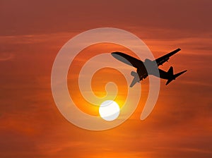 Silhouette passenger airplane flying on sunset