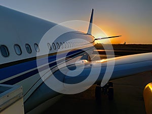 Silhouette of a passenger airplane landing on the airport apron against backdrop of the picturesque orange sunset sky