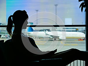 SILHOUETTE: Passenger holding her phone while looking through the airport window