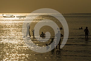 Silhouette of people at beach basking to golden light during sunset.