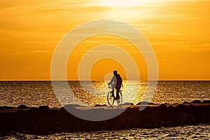 Silhouette of people biking on the pier during the golden hour of sunset