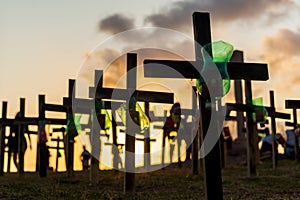 Silhouette of people and crosses fixed on the ground in honor of those killed by covid-19