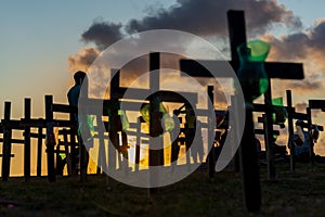 Silhouette of people and crosses fixed on the ground in honor of those killed by covid-19