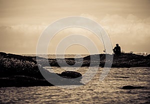 Silhouette of people fishing by the sea